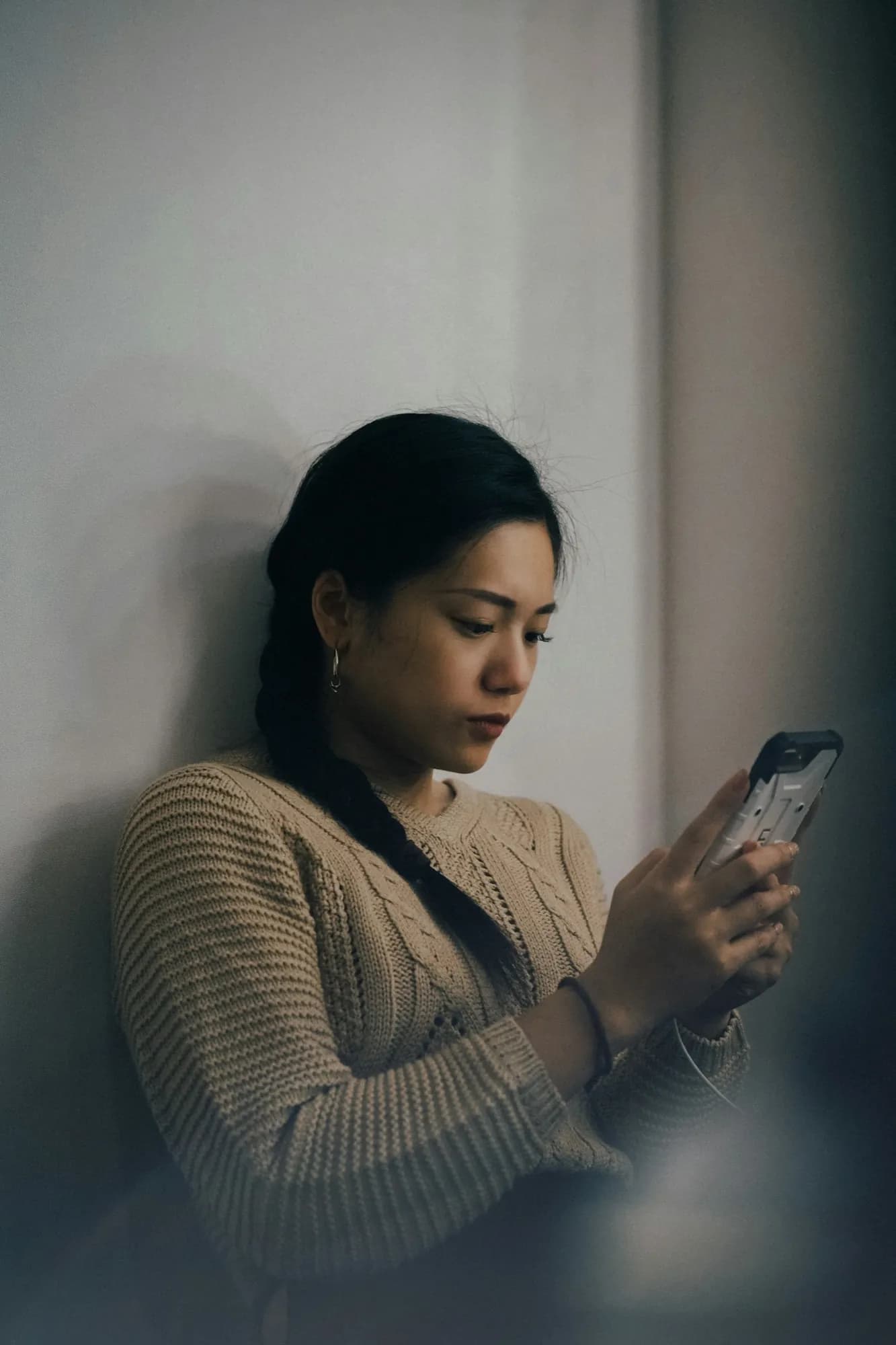 A customer leaning against a wall, booking on her phone